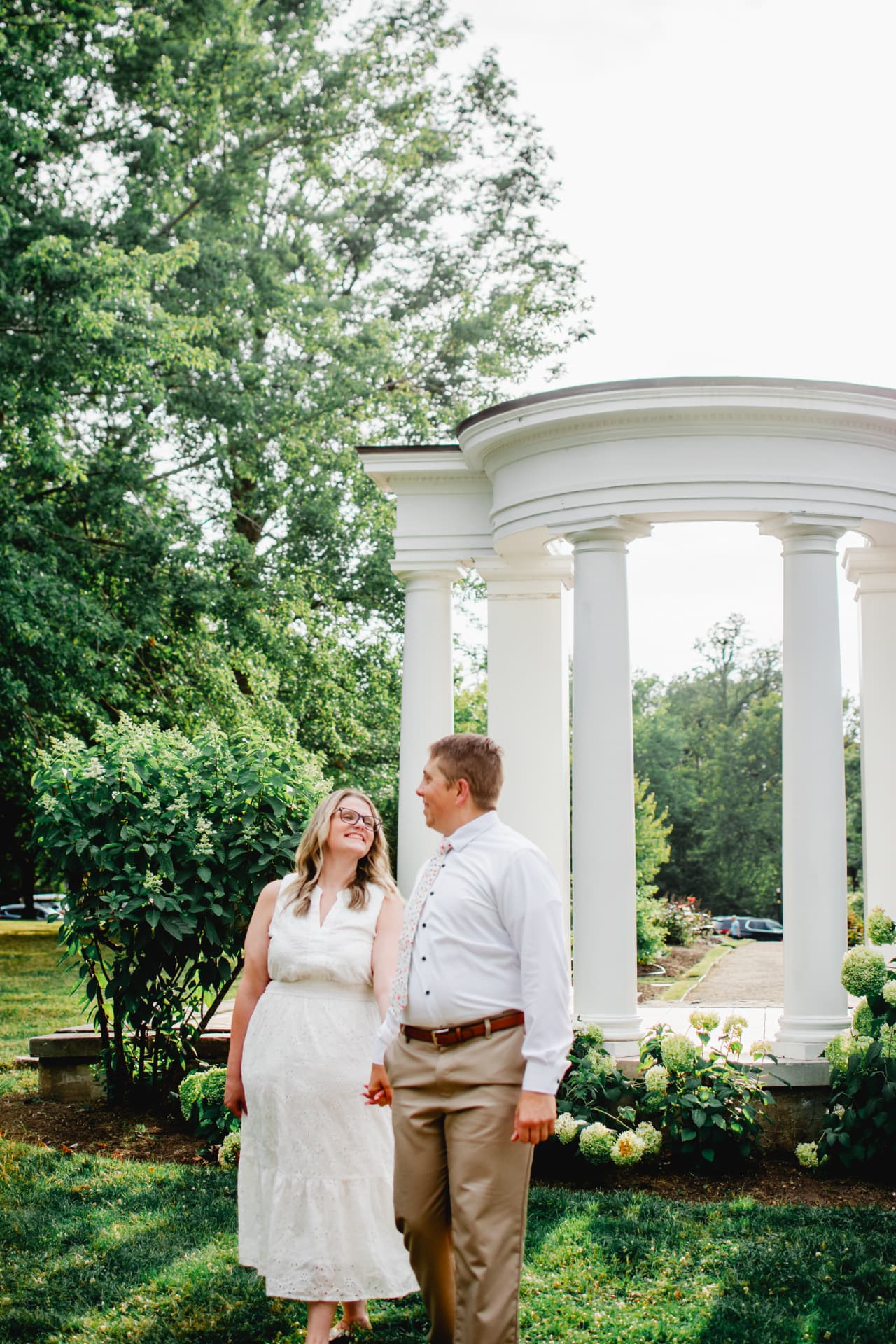 Engaged couple holding hands beside a garden rotunda